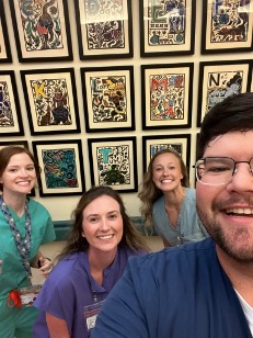 selfie featuring fur residents with backdrop of alphabetized artwork on a display wall